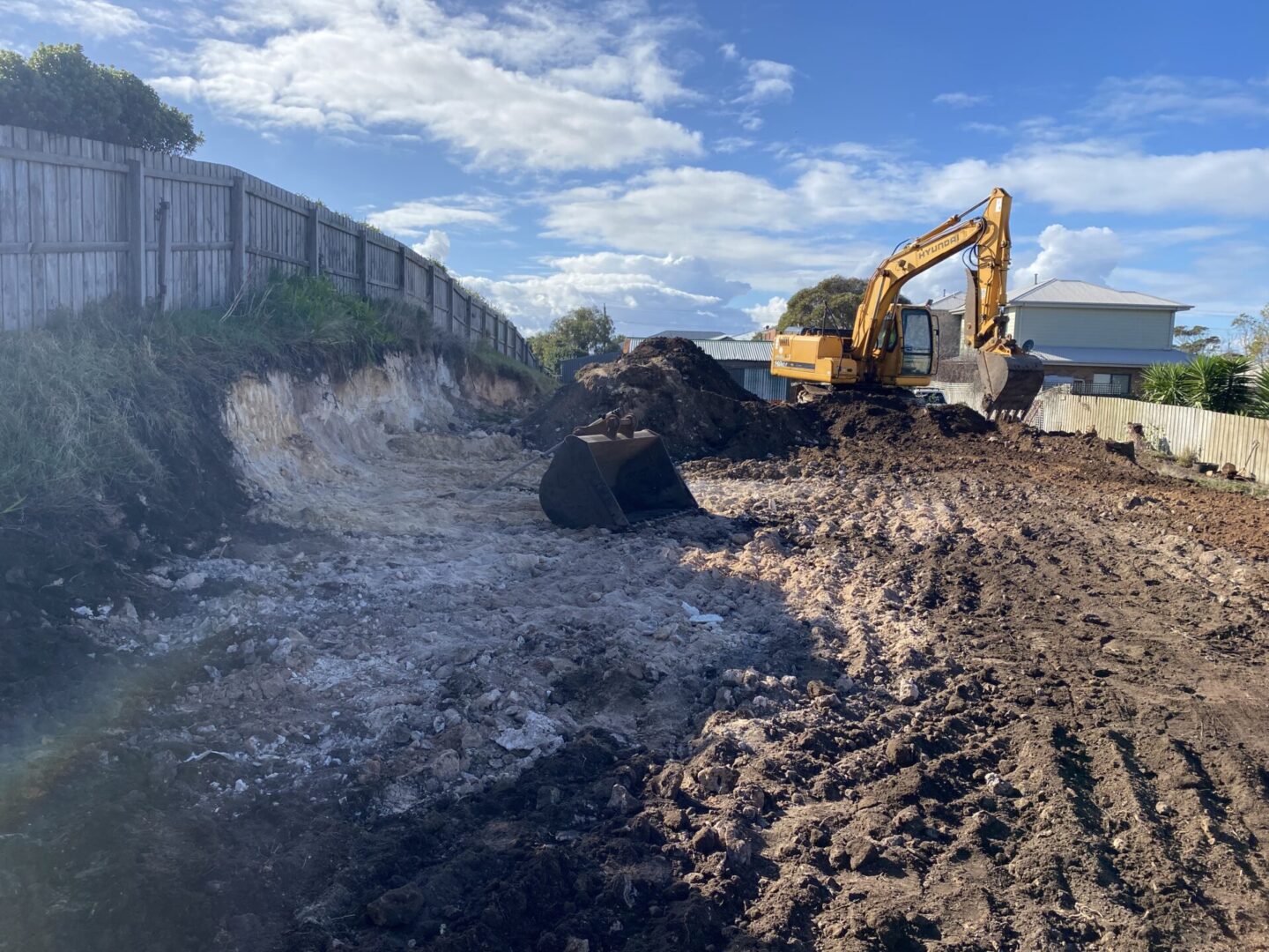 Excavator digging soil in residential construction site.